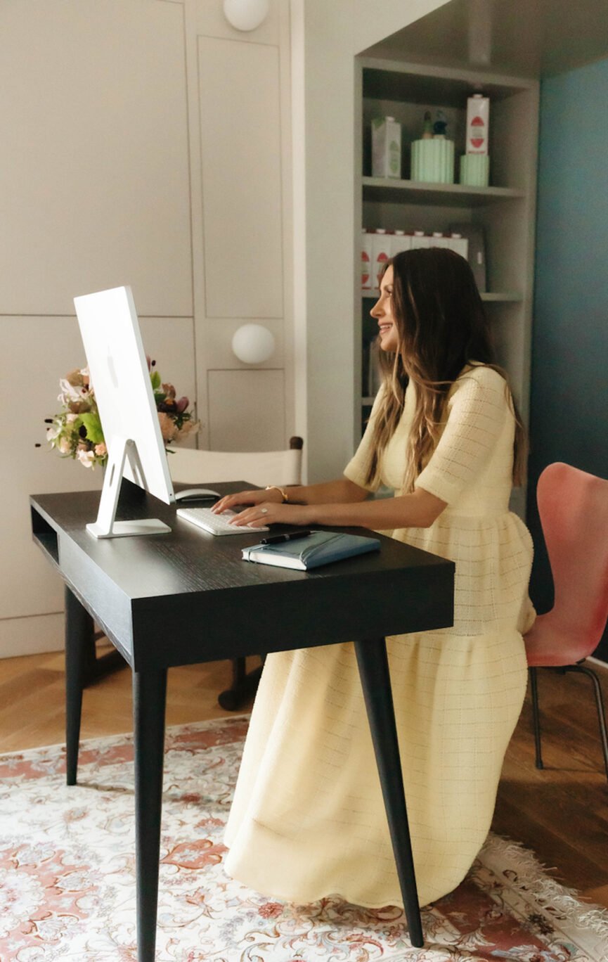 Woman typing on laptop in home office.