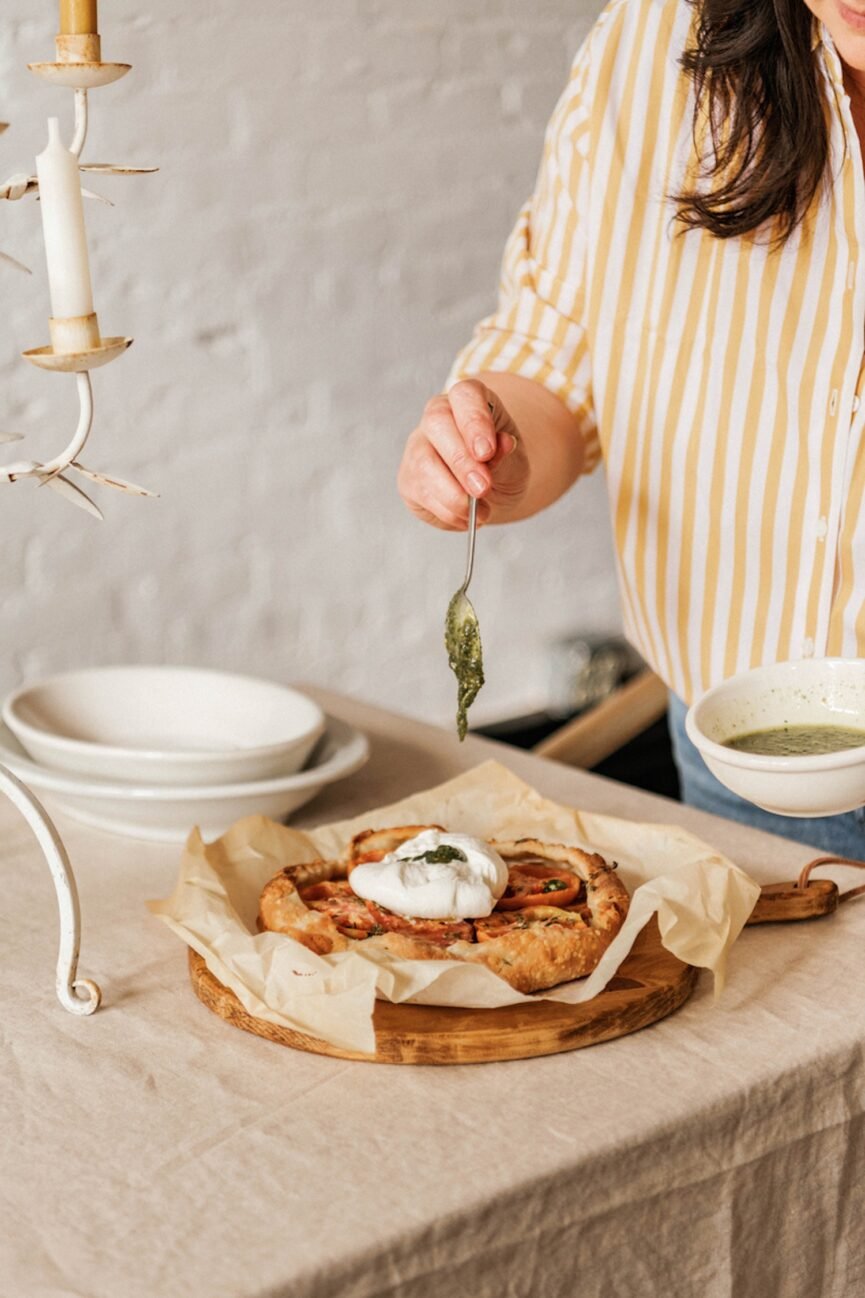 Woman making pesto burrata galette.