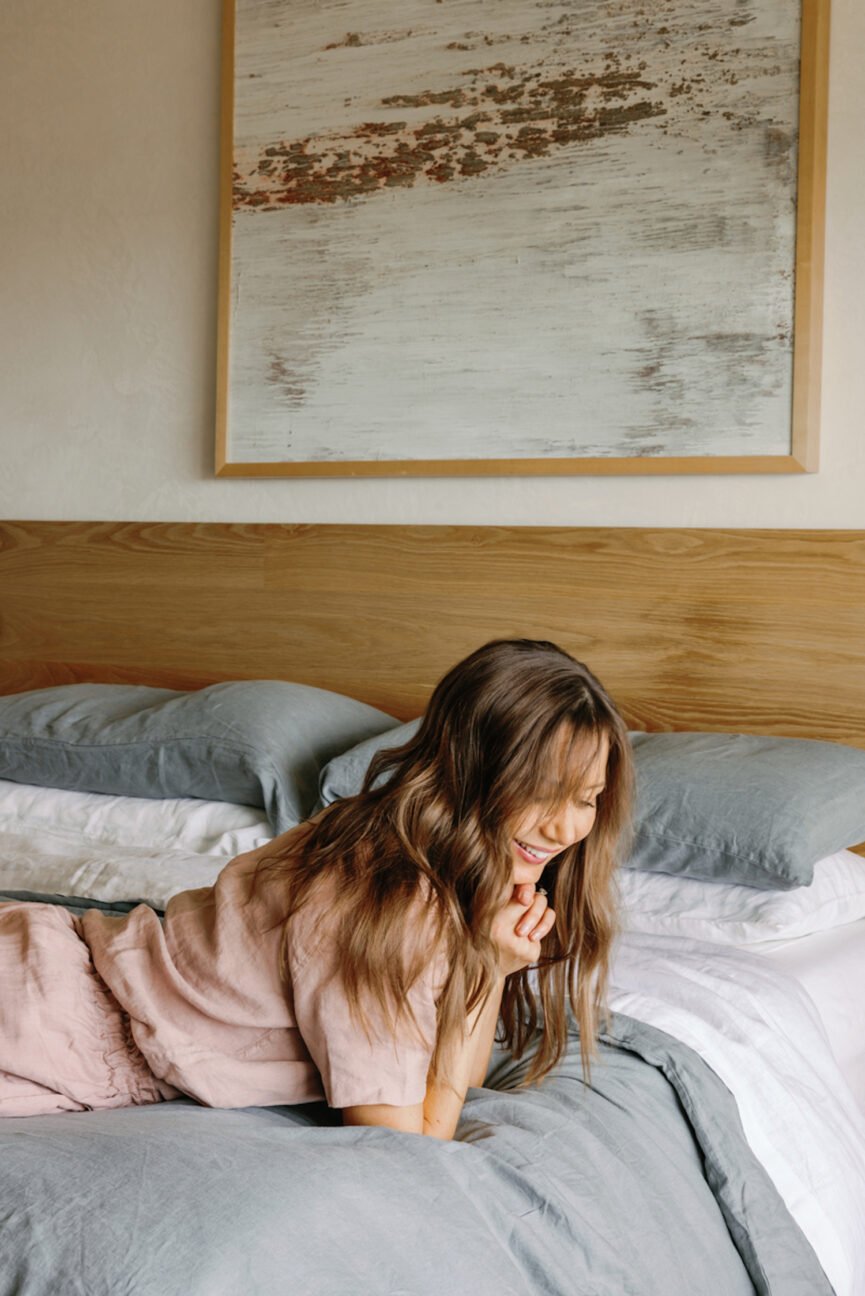 Woman laughing in bed thinking about setting social media boundaries.