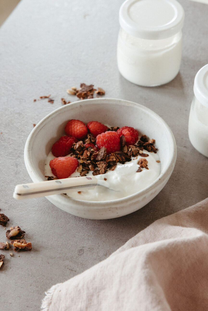 Tigela de iogurte probiótico com granola e framboesas