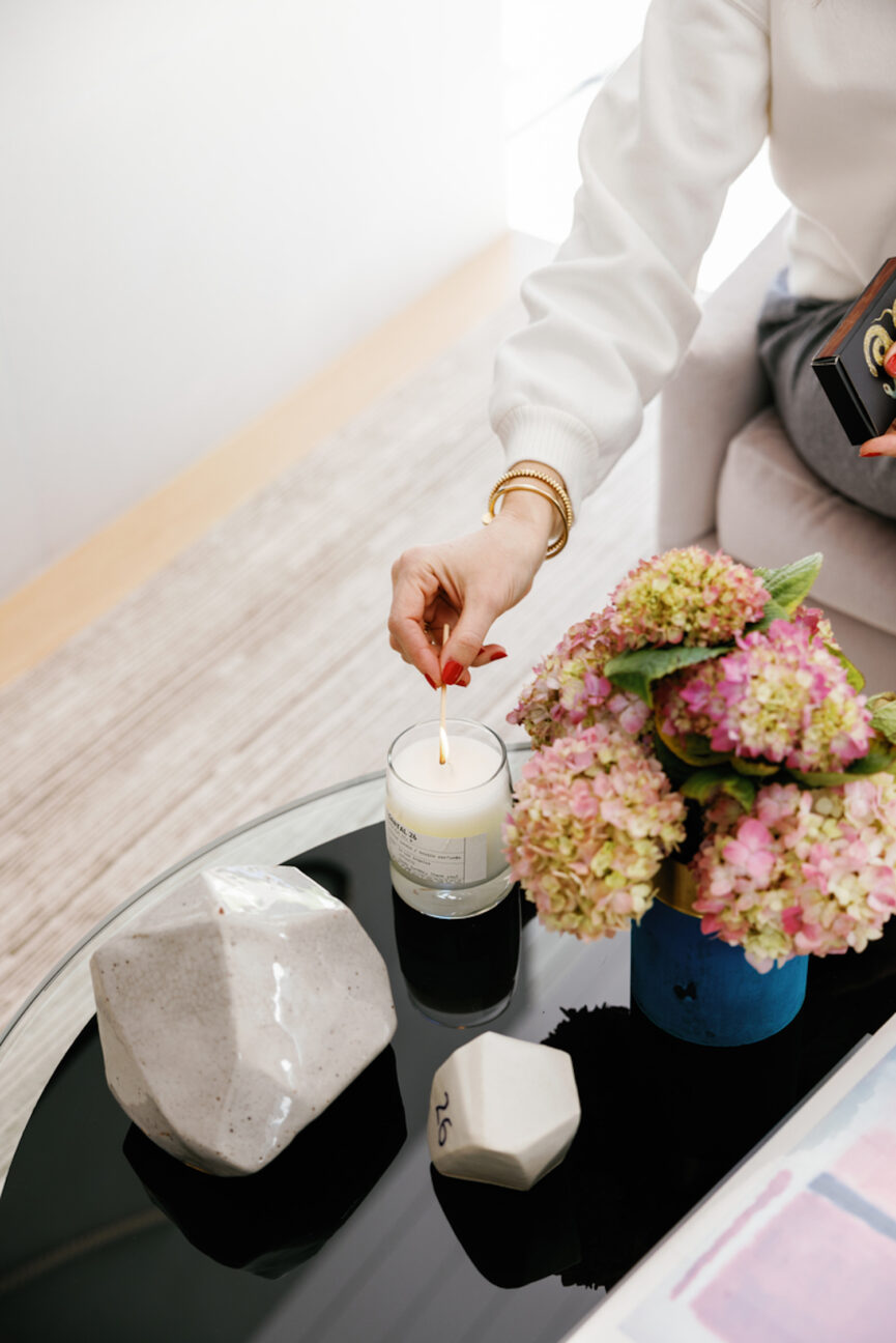 Woman lighting candle on coffee table.