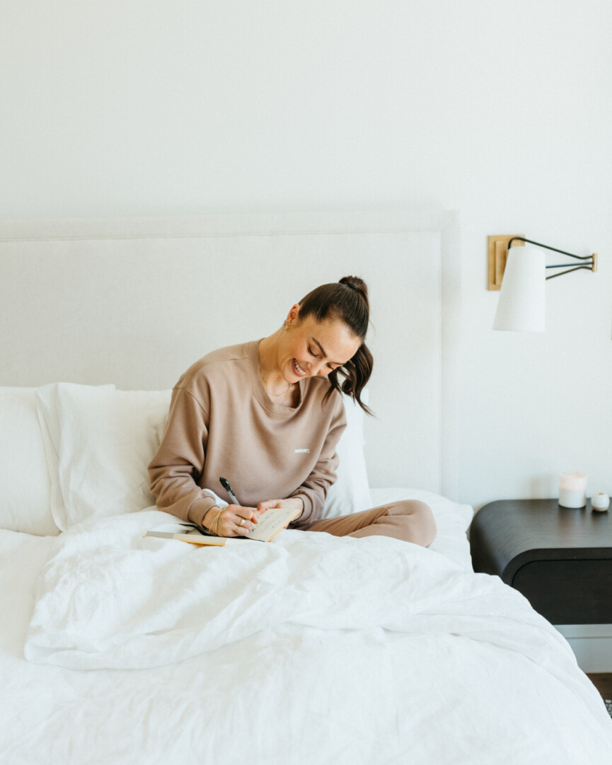 Woman writing diary while lying in bed