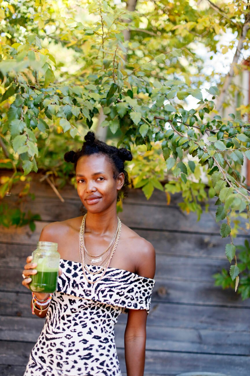 Woman drinking green juice outside.