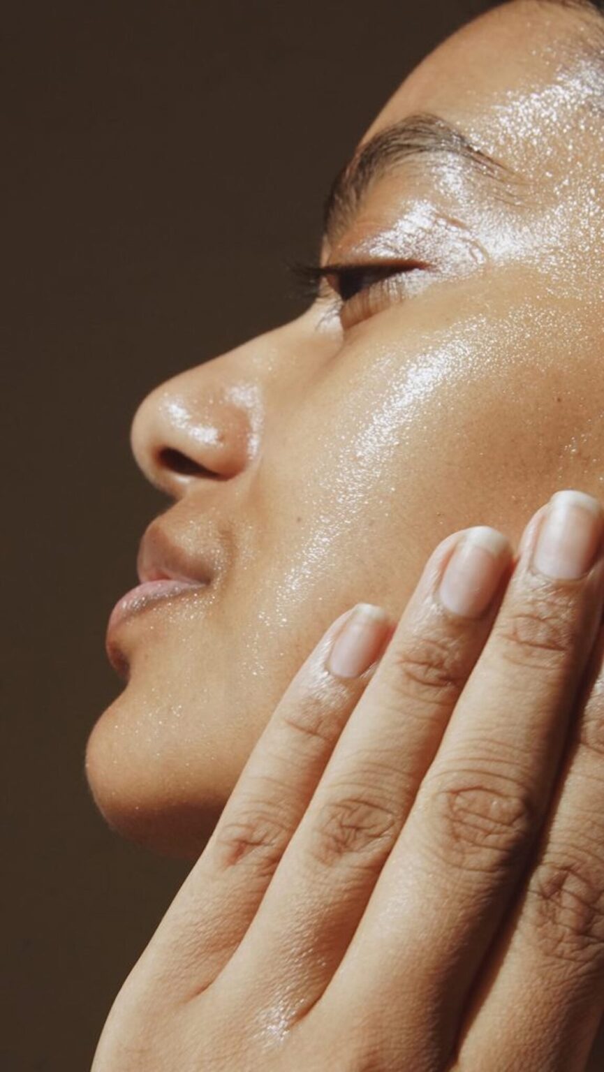 Woman with glowy skin applying olive oil to face.