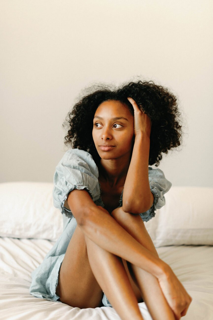 Woman in pajamas sitting on bed.