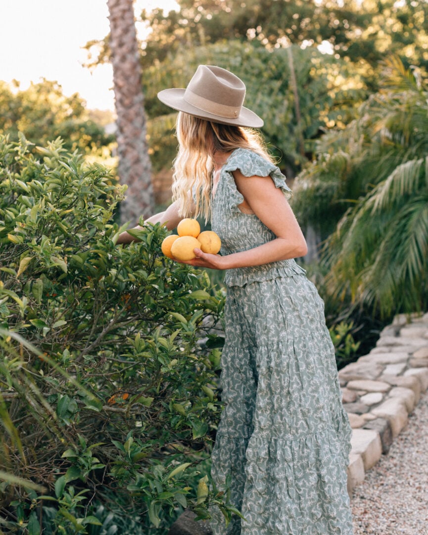 Woman picking lemons outside.