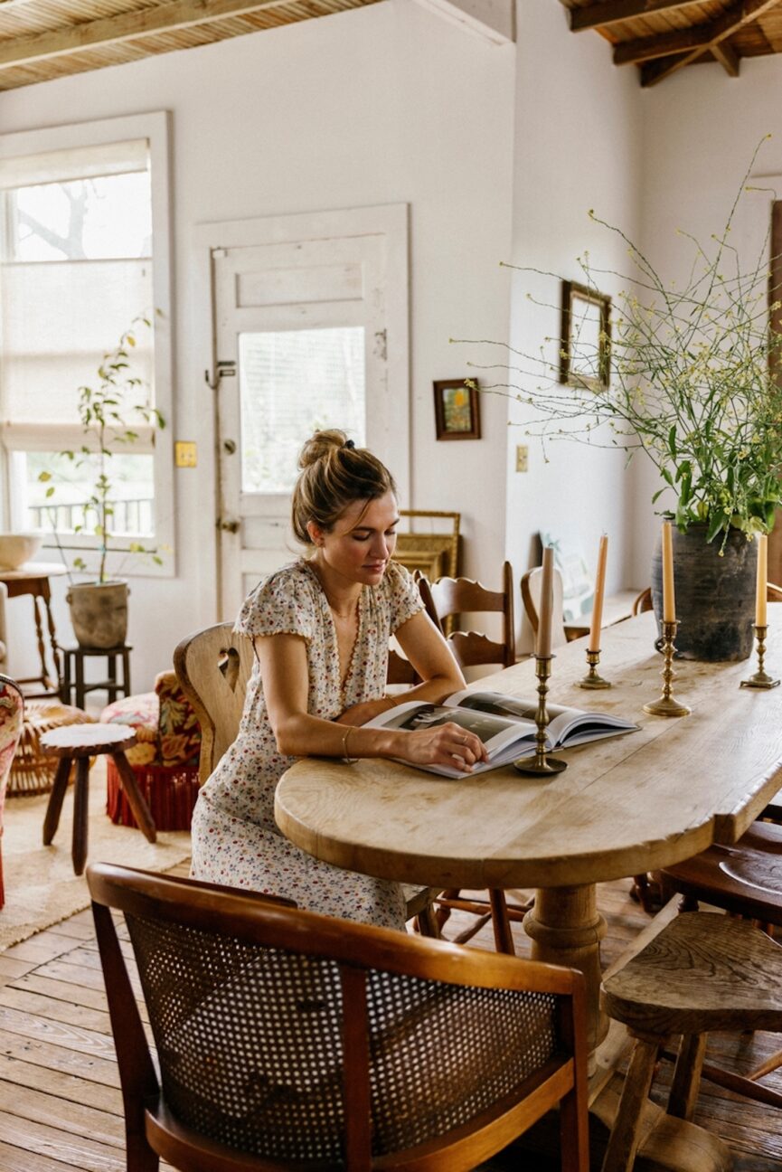 A woman sits at a table reading one of the best new books of fall 2024.