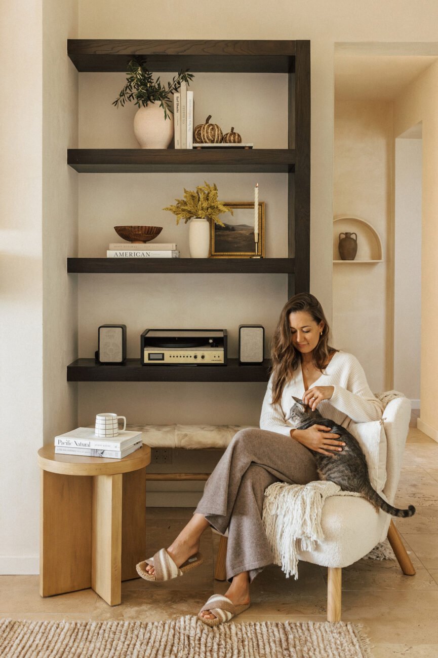 Camille Styles petting cat in cozy fall living room.