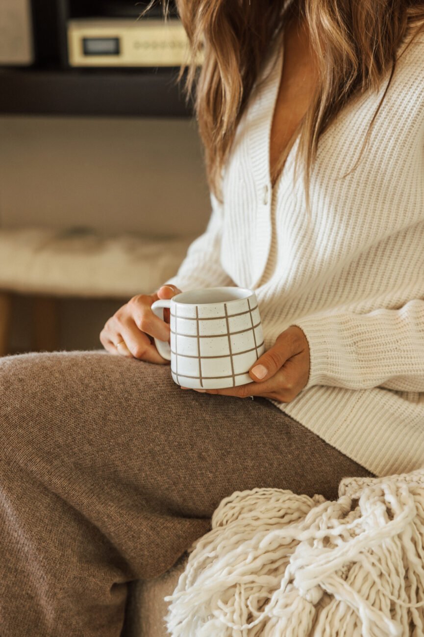 Mujer bebiendo de una acogedora taza de otoño.