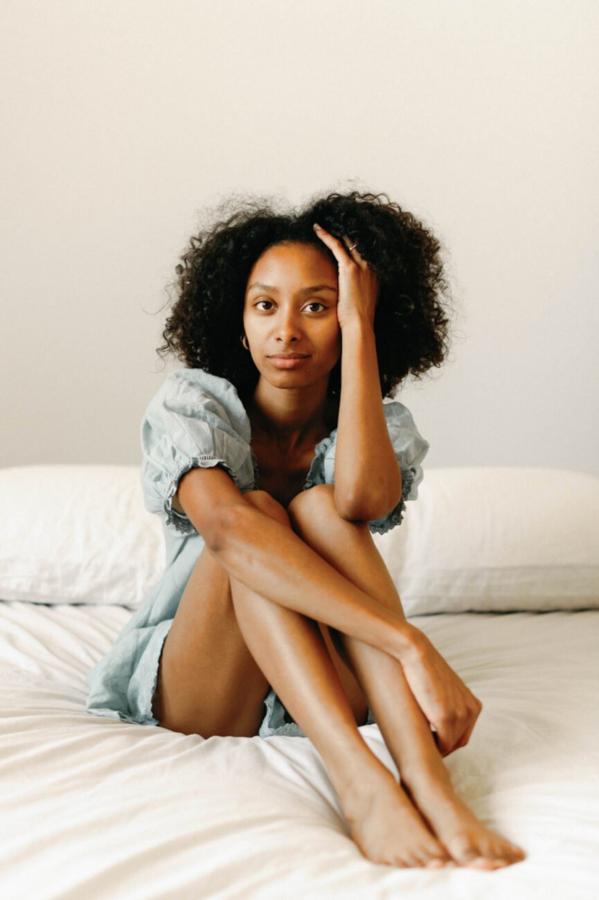 Woman wearing nightgown sitting on bed.