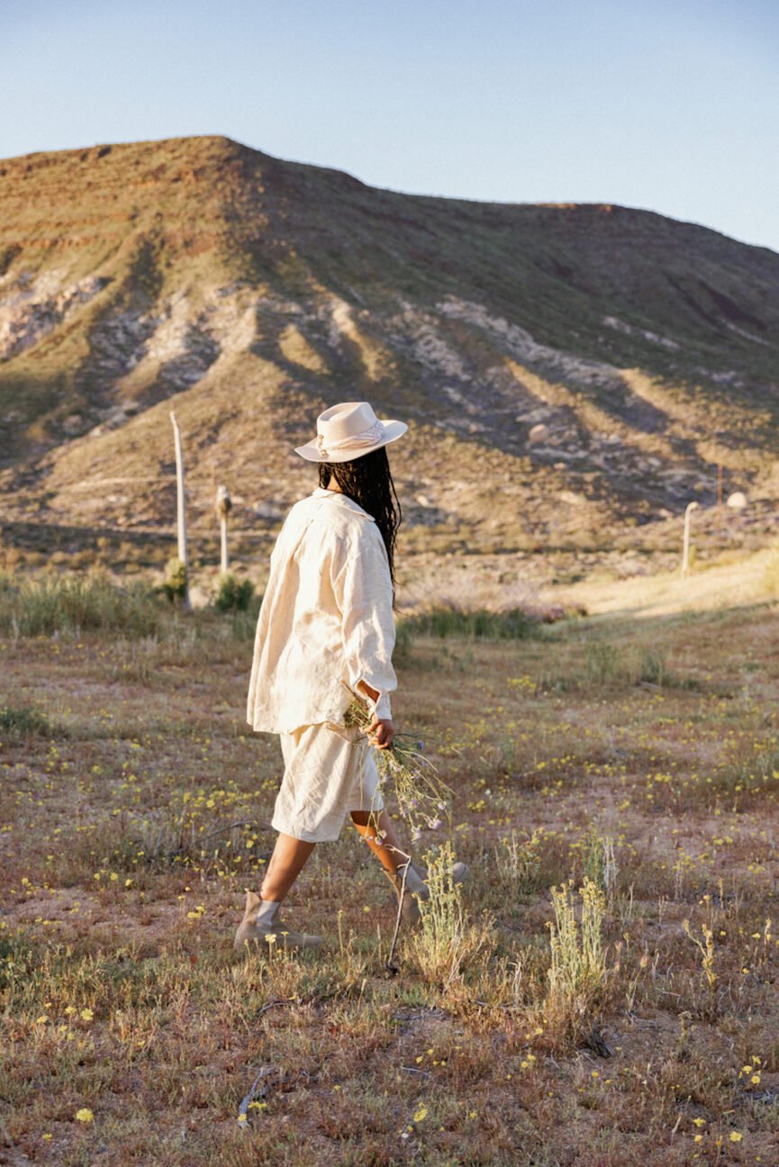 Mujer caminando en el campo sosteniendo flores