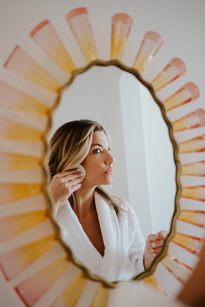 Woman massaging face in mirror.