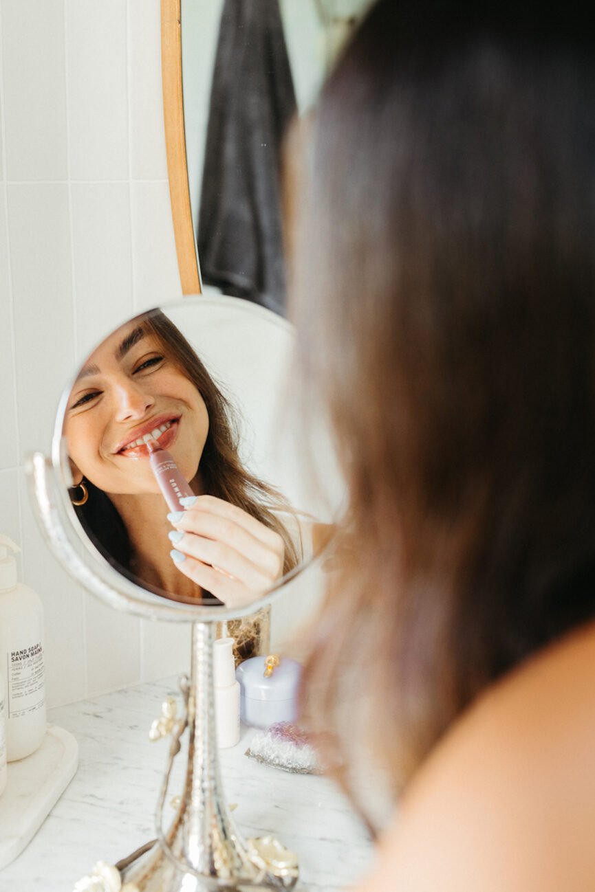 Woman applying makeup in mirror.