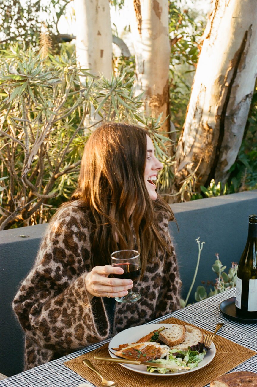 Mulher rindo com vinho na mão