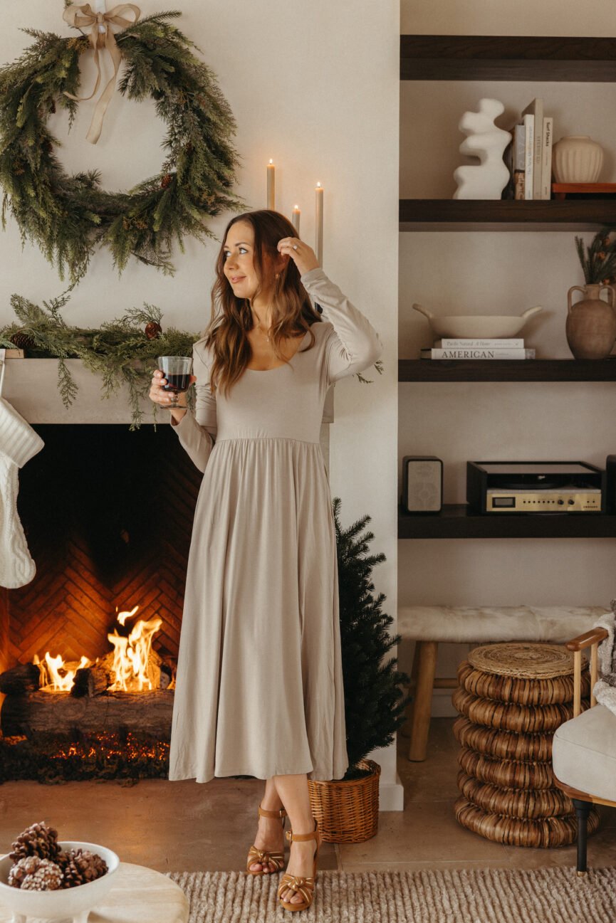 Camille Styles drinking wine by holiday mantel