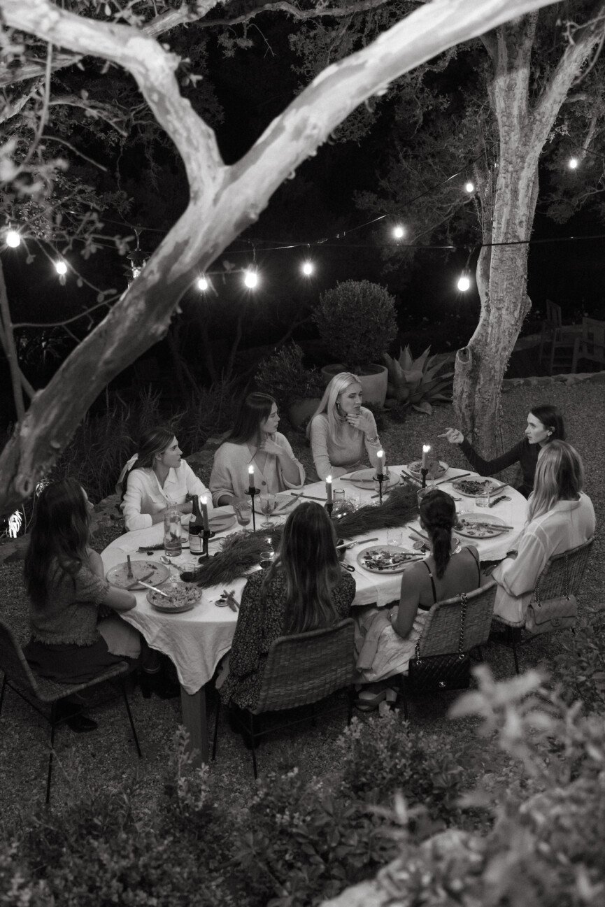 Friends at holiday backyard dinner party around table at night