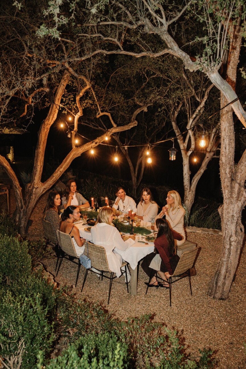 Friends at holiday backyard dinner party around table at night