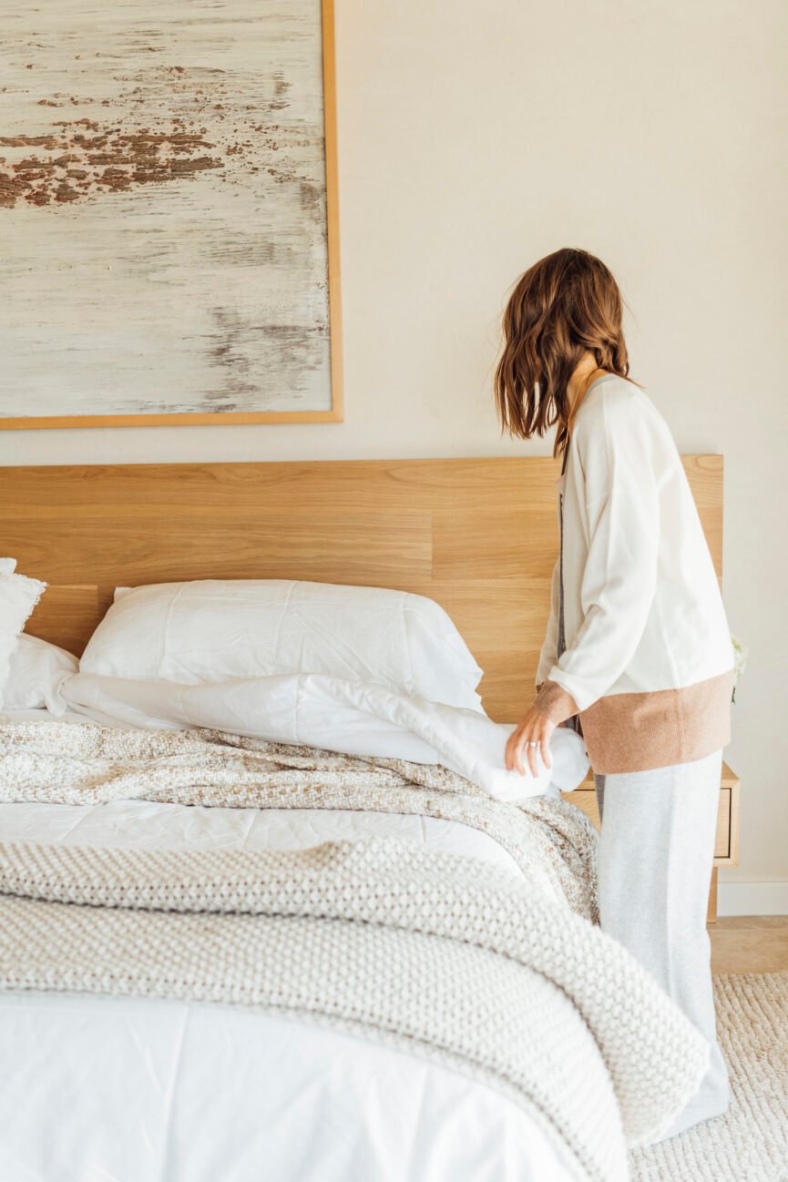 Woman making the bed thinking about what is mindful sex.