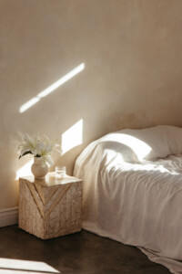 sunlight on a wall behind a minimal bed