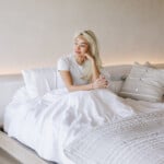 Woman sitting in bed experiencing summer fatigue.