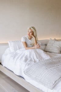 Woman sitting in bed experiencing summer fatigue.
