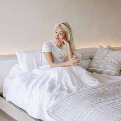 Woman sitting in bed experiencing summer fatigue.