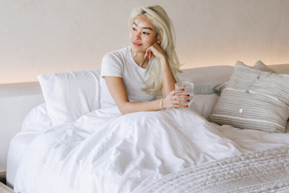 Woman sitting in bed experiencing summer fatigue.