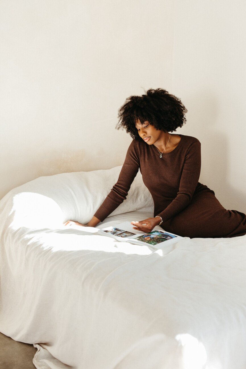 woman reading book on bed
