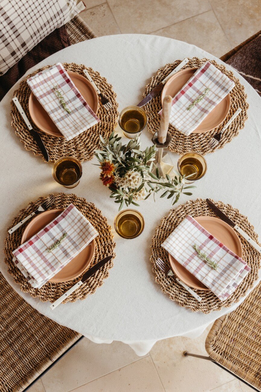dining room table with plaid napkins, silverware, and clay plates