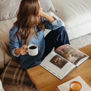 camille sitting at coffee table with book and coffee