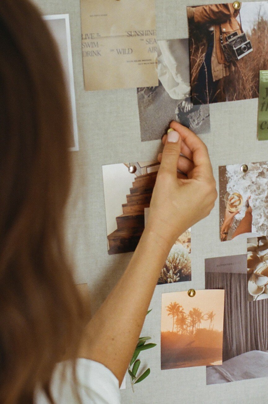 Hands pinning photos and quotes to a linen vision board