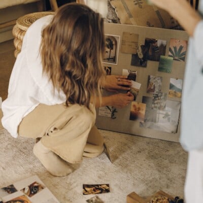 Hands pinning photos and quotes to a linen vision board