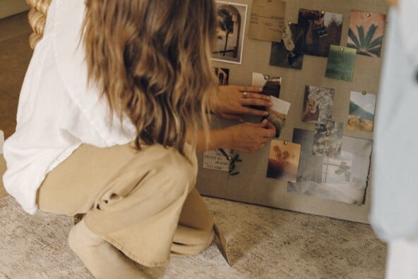 Hands pinning photos and quotes to a linen vision board