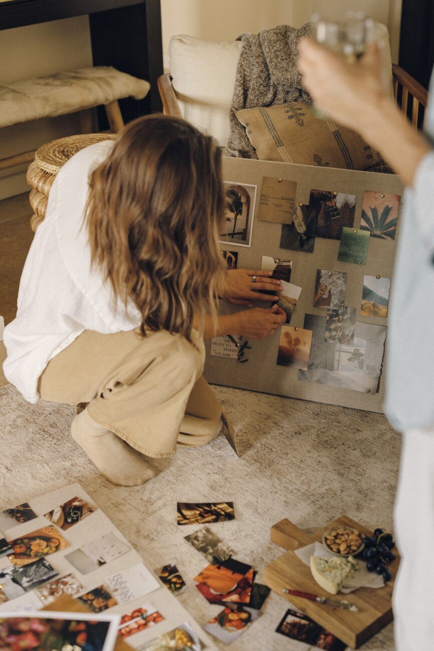Hands pinning photos and quotes to a linen vision board