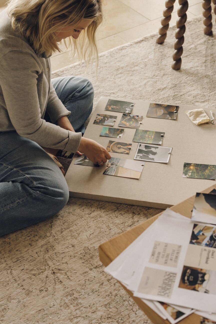 Hands pinning photos and quotes to a linen vision board