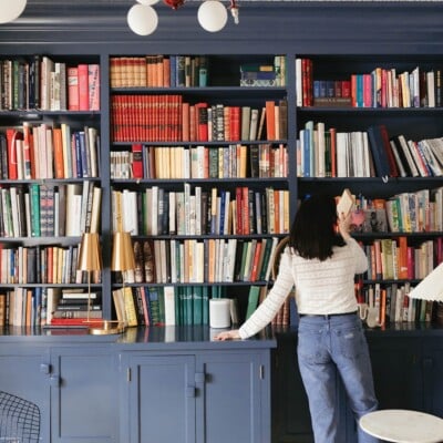 Woman taking book off a shelf.