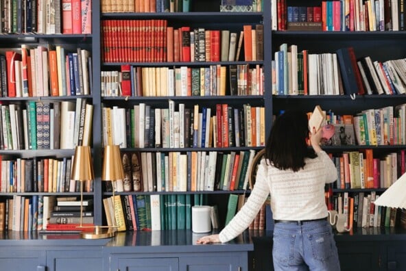 Woman taking book off a shelf.