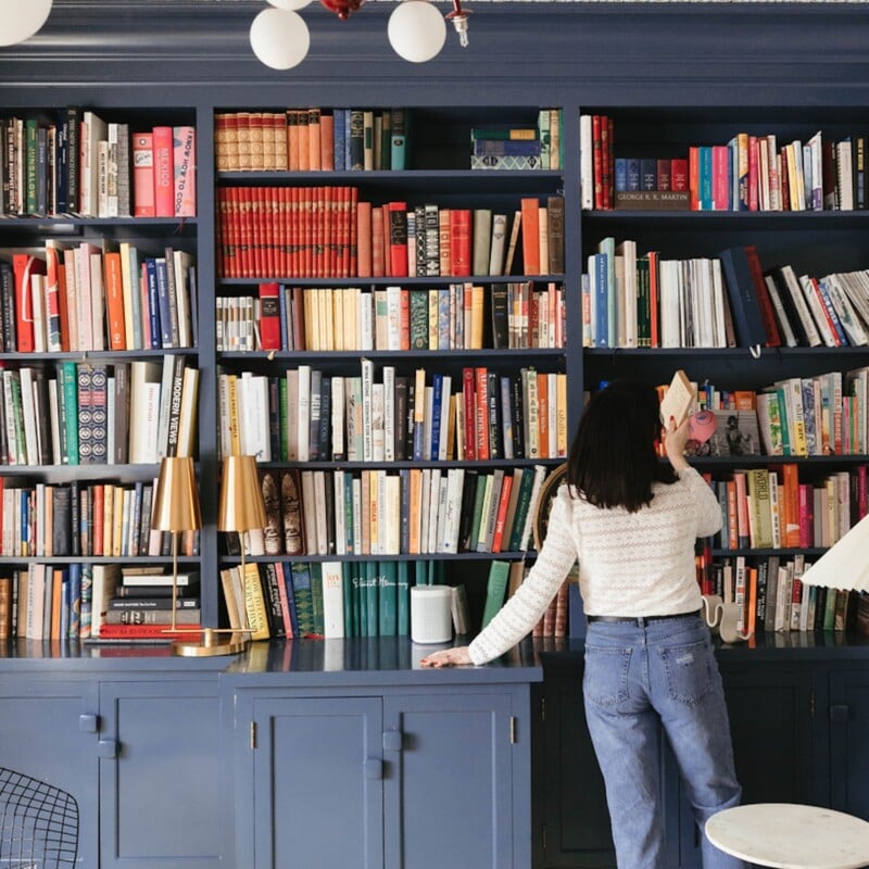 Woman taking book off a shelf.