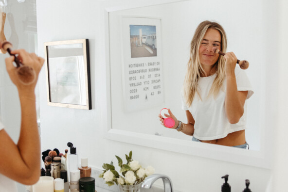 Woman applying makeup in mirror.