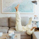 Woman reading magazine on couch.