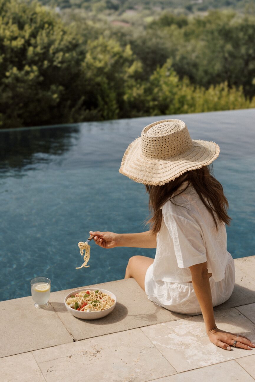 Woman eating pasta by the pool.