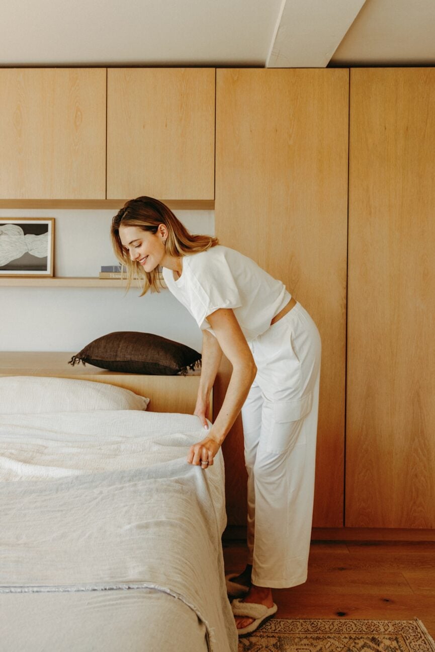 Mulher arrumando a cama como parte de seus rituais matinais para maior clareza.