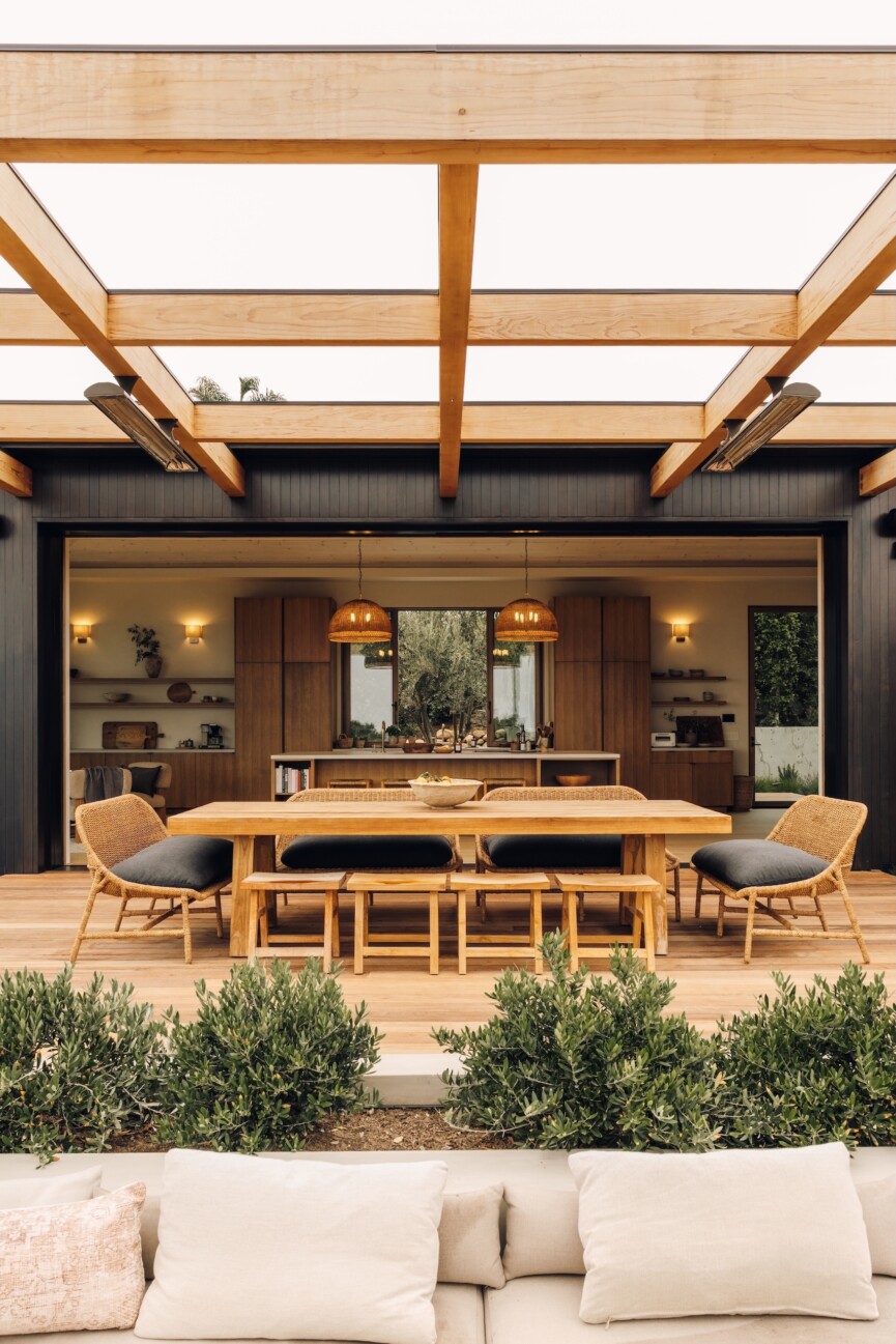 Casa Zuma’s outdoor dining terrace with an oak table, woven chairs and open views into the kitchen.