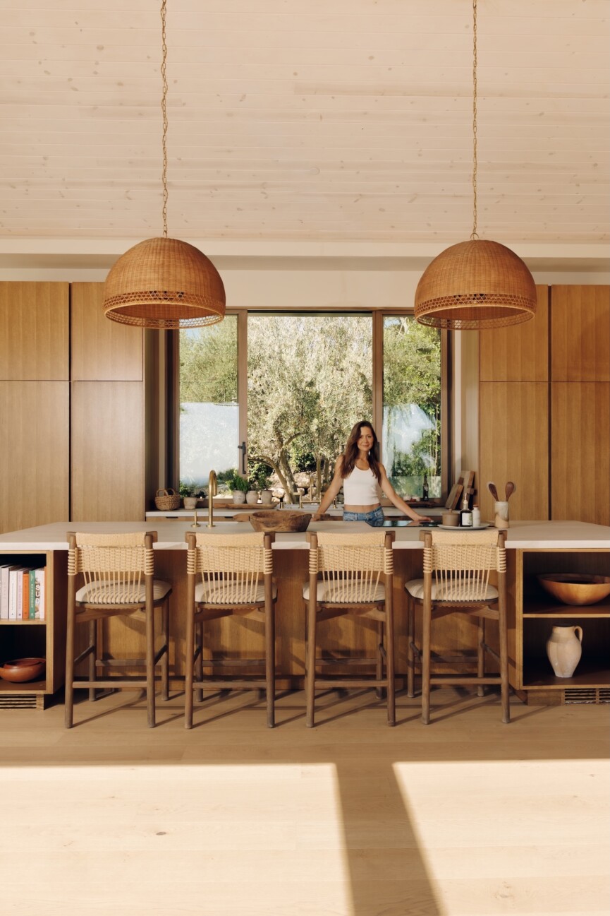 Camille Styles in her Malibu great room, featuring an oak kitchen island, wood cabinetry and woven pendant lights.
