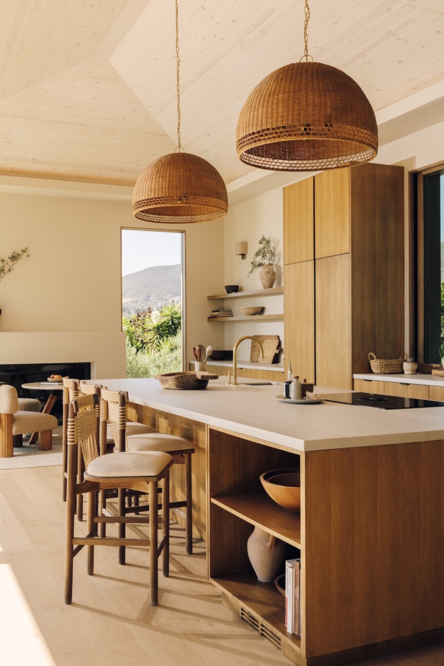 Oak kitchen island with woven Casa Zuma pendant lights and wood counter stools in Camille Styles’ Malibu great room.