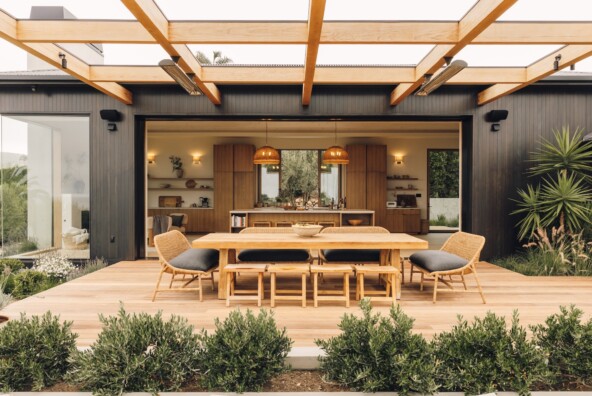 Open pocket doors connect Casa Zuma’s kitchen and great room to an outdoor dining terrace surrounded by greenery.