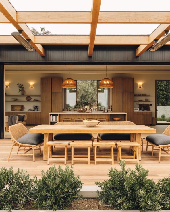 Open pocket doors connect Casa Zuma’s kitchen and great room to an outdoor dining terrace surrounded by greenery.