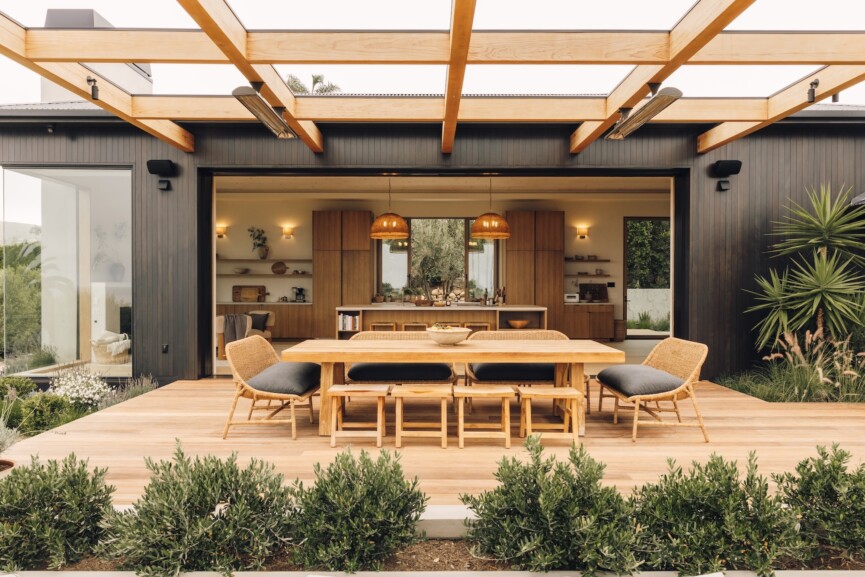 Open pocket doors connect Casa Zuma’s kitchen and great room to an outdoor dining terrace surrounded by greenery.