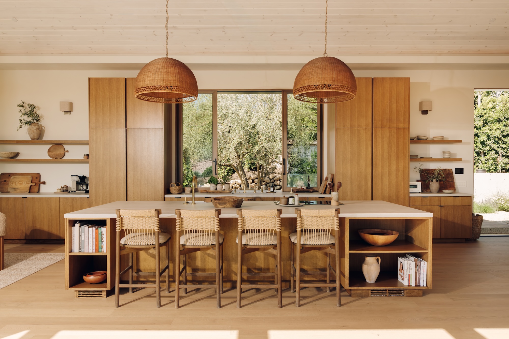 Camille Styles' Malibu great room, featuring an oak kitchen island, wood cabinetry and woven pendant lights.