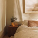 Neutral linen bedding and a wood nightstand styled with a small lamp in Camille Styles’ daughter’s bedroom.